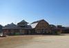 青空と広い運動場から見た、茶色の建物の竹田幼稚園外観写真
